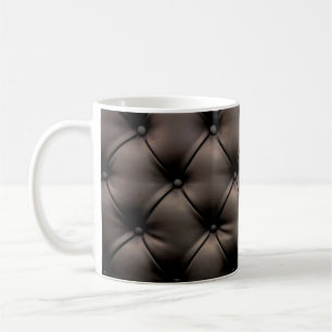 Ein dunkles Lederkissen als Hintergrund, von einem Kaffeetasse
