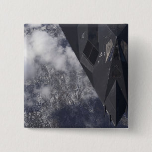 Ein F-117A-Nachtwächter fliegt hoch über dem Berg Button