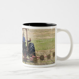 Ein junger Junge, der ein Traktorernten fährt Zweifarbige Tasse