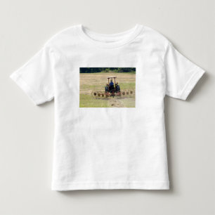 Ein junger Junge fährt einen Traktor zur Ernte Kleinkind T-shirt