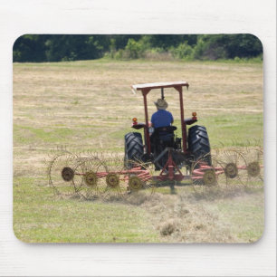 Ein junger Junge fährt einen Traktor zur Ernte Mousepad