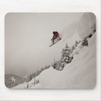 Ein Snowboarder springt von einer Klippe in Puder