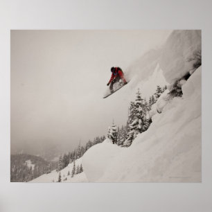 Ein Snowboarder springt von einer Klippe in Puder Poster