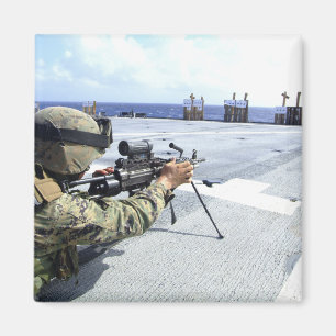 Ein US-Marinesoldat, der seine Waffe justiert Magnet