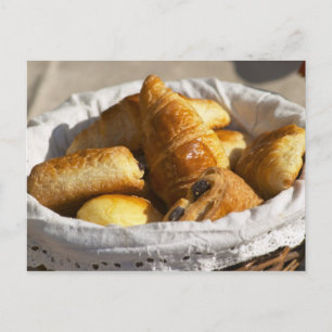 Ein Weiden-Frühstückskorbe mit Croissants und Postkarte