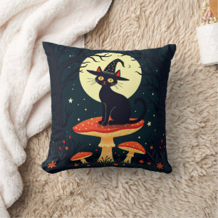 Eine kleine schwarze Hexenkatze sitzt auf einem Gi Kissen