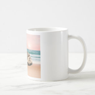 Eine süßere gestreifte Katze sitzt am Strand bei S Tasse