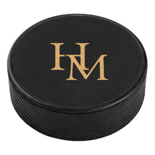 Elegantes schwarzes Puck mit goldener Monogrammbes