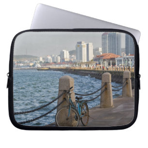 Fahrrad am Wasser mit der Skyline der Stadt Yantai Laptopschutzhülle