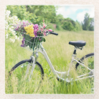 Fahrrad mit Korb der Blume auf der Wiese Glasuntersetzer