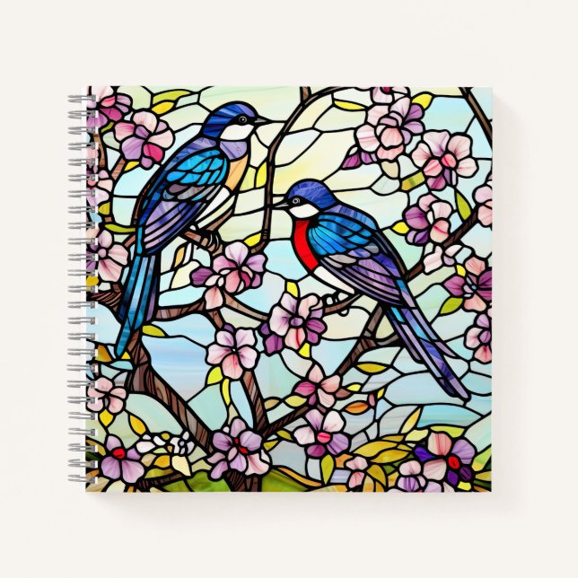 Farbenfrohe, festgeklemmte Glasvögel auf blühenden Notizbuch (Vorderseite)