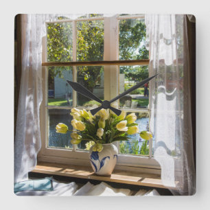 Fenster mit Spitzen-Vorhang und Tulpen Quadratische Wanduhr