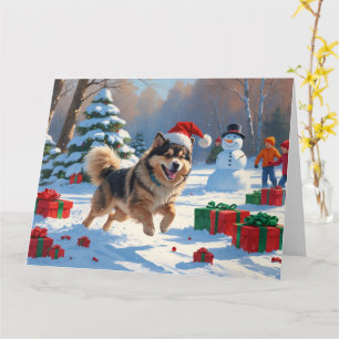 Finnischer Lapphund läuft durch Schnee mit Weihnac Karte