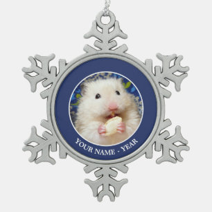 Flaumiger syrischer Hamster Kokolinka, das einen Schneeflocken Zinn-Ornament