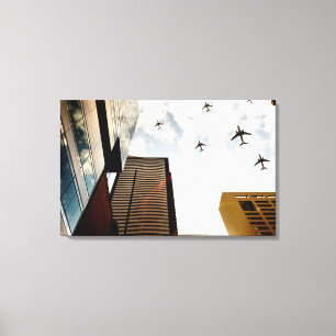 Flugzeuge, die über Gebäude fliegen Leinwanddruck