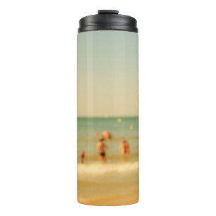Foto am Strand unscharf. Leute, die sich entspanne Thermosbecher