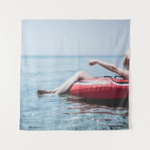 Frau auf einem aufblasbaren Schwimmer im Ozean, de Wandteppich