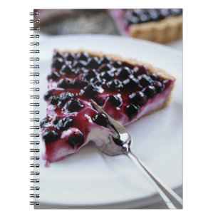 Gabel, die Heidelbeerkuchen auf Platte schneidet Notizblock