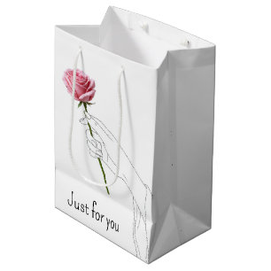 Geburtstagsfrau hält eine rosa Rose in der Hand Mittlere Geschenktüte