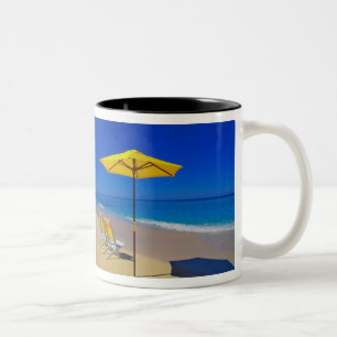 Gelber Strandsonnenschirm und Stühle auf makellose Zweifarbige Tasse