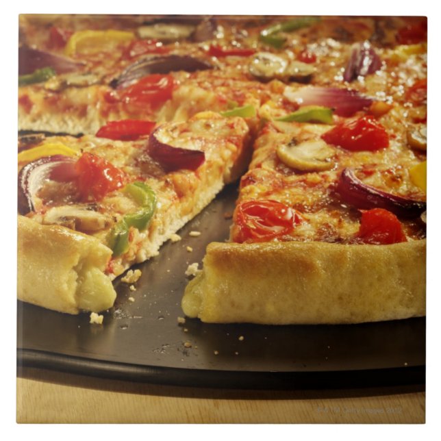 Gemüsepizza geschnitten auf schwarzer Wanne auf Fliese (Vorderseite)