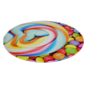 Gestreifter Lutscher und mehrfarbige Smarties Schneidebrett