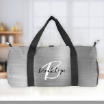 Glam Silver Brushed Metal Schwarz-weiß Monogram Duffle Bag<br><div class="desc">Diese personalisierte Duffeltasche ist mit einem Monogramm und einem Vornamen in modernem Schwarz-Weiß-Drehbuch auf einem glamourösen silbernen Imitat gebürstet Metall Hintergrund.</div>