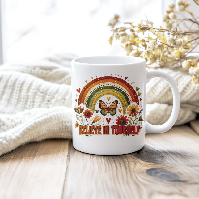Glauben Sie an Ihre selbst Boho Rainbow Blume Butt Kaffeetasse (Believe in Yourself Boho Rainbow Flowers Butterfy Coffee Mug on a neutral cozy wooden table.)