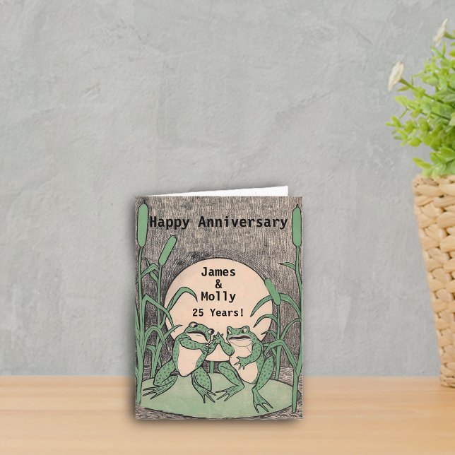 Glücklicher 25. Jahrestags-grüne Karte (Two cute argueing green frogs on lily pad full moon on Happy anniversary card.)