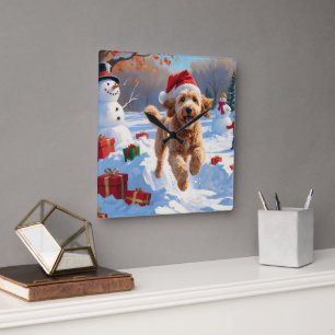 Goldendoodle läuft im Schnee mit Weihnachtsmütze Quadratische Wanduhr