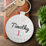 Golf Ball Dimples mit schwarzem Namen Schlüsselanhänger<br><div class="desc">Ein sportliches und männliches Motiv für die Typ und Jungen in Ihrer Familie. Dieses Sportdesign ist perfekt für jeden Sportler geeignet. Es sieht aus wie ein Foto einer Goldkugel. Sie können dies als Happy Birthday Gefallen verwenden und die Anzahl Jahre alt im Zahlenbereich einbeziehen.</div>