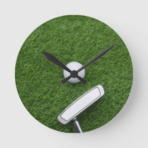 Golf ball with putter are on green grass runde wanduhr