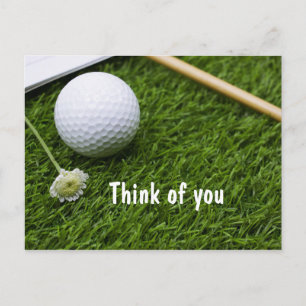 Golfball mit einer kleinen Blume auf Gras denken S Postkarte