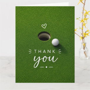 Golfball neben Loch auf grünem Gras Danke  Karte