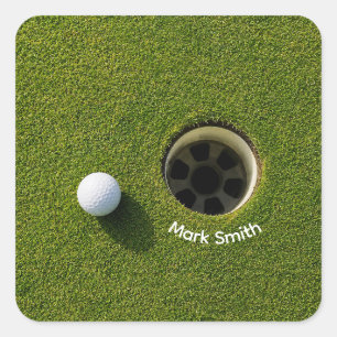 Golfball neben Loch auf grünem Rasen Golfplatz Quadratischer Aufkleber