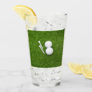Golfball und Abschlag sind auf grünem Gras Glas