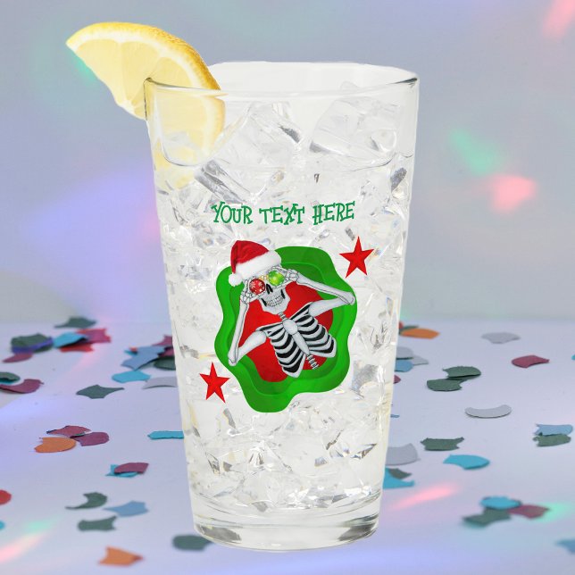 Goofy Christmas Skeleton Ornament Eyes im Spritzer Glas (Silly skeleton ornament eyes splatter shape red stars on Merry Christmas glass drink tumbler.)