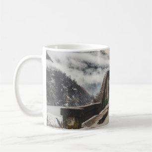 GRAUE BETONBOGENBRÜCKE NEBEN BLATTLOSEM BAUM IN DE KAFFEETASSE