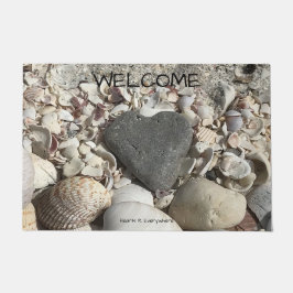 Grauer Herzstein auf großer Fußmatte des Strandes