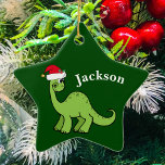 Green Christmas Kids Dinosaur Keramikornament<br><div class="desc">Phantastischer grüner Dinosaurier lächelt und sieht sehr niedlich in einem Urlaub roten Weihnachtsmannmütze. Ich mag prähistorische Weihnachtstiere und Geschenke,  die Kinder Liebe. Passen Sie dieses Geschenk mit dem Namen des Empfängers an,  um es noch personalisierter zu machen.</div>