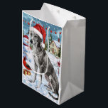 Greyhound Winter Wonderland Christmas Joy Mittlere Geschenktüte<br><div class="desc">Dieses festliche Design spiegelt den fröhlichen Geist der Urlaubssaison wider und besticht durch ein hübsches Jungtier mit einer Weihnachtsmannmütze. Der Hund ist eingebettet in ein winterliches Wunderland, mit einem Schneemann, einem dekorierten Weihnachtsbaum und wunderschön verpackten Geschenken. Schneeflocken fallen sanft ab und geben der Szene eine magische Touch, während die lebhaften...</div>