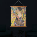 Gustav Klimt-Lady mit einem Fan | Wandteppich Mit Holzrahmen<br><div class="desc">Gustav Klimts "Lady with a Fan" ist ein faszinierendes Porträt, das das Wesen der Jugendstil- und Jugendstil-Bewegungen erahnen lässt. Das Gemälde zeigt eine Regalfrau, ihren Blick direkt und selbstbewusst, und hält einen verzierten Fan in der Hand. Sie ist in einem Kleid geschmückt, das eine Symphonie von reichhaltigen Mustern und Texturen...</div>