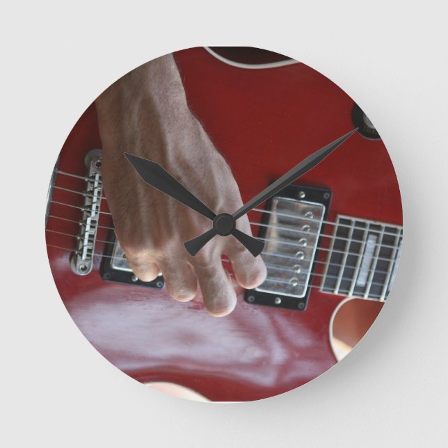 Hand, die rote elektrische Gitarre nahe Runde Wanduhr (Vorderseite)