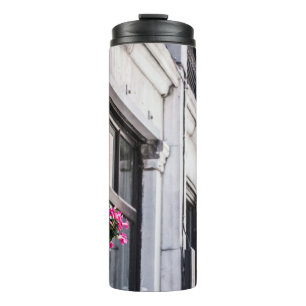 HARTPINK-BLUME AUF WEISS KONKRETEN GEBÄUDE AM TAG THERMOSBECHER