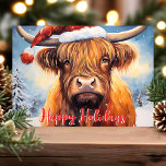Highland Cow Santa Hat Cute Weihnachten<br><div class="desc">Feiern Sie die Urlaubssaison mit dieser bezaubernden Weihnachtskarte mit einer bezaubernden Hochlandkuh mit einem Weihnachtsmütze. Die festliche Szene umfasst schneebedeckte Bäume und einen fröhlichen "Happy Holidays" Gruß in Rot. Diese Karte ist perfekt, um Ihren Feiertagsgruß mit einem Hauch von Laune und Wärme zu erfüllen. Sie wird jedem ein Lächeln ins...</div>