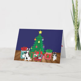 Huskies, der unter der Weihnachtsbaum-Karte spielt Feiertagskarte