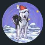 Husky Christmas Runder Aufkleber<br><div class="desc">Animal Parade Festival Husky Hund Weihnachtsgeschenke und Zubehör, die Ihnen von Stellen Sie sich das! Design zeigt unsere originelle Kunst eines niedlichen, schwarz-weißen sibirischen Huskys, der für den Urlaub mit einer kräftig roten Weihnachtsmannmütze auf seinem Kopf und einem festlich grünen heiligen Kranz auf seinem Hintern mit einem fröhlichen roten Bogen...</div>
