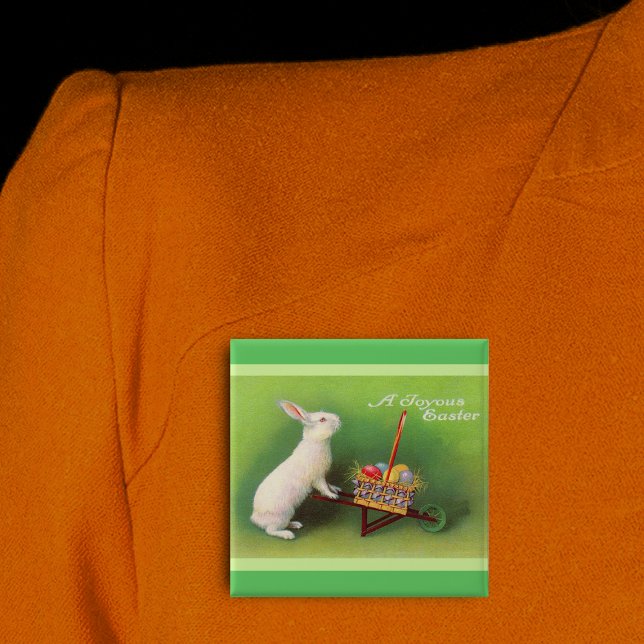 Joyous Oaster Rabbit Basket Eggs Button (Joyous Easter white rabbit pushing wheelbarrow coloured eggs on green pin back button.)