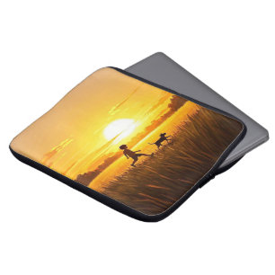 Junge Junge, die mit Hund bei Sonnenuntergang renn Laptopschutzhülle