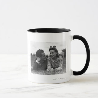 Junge Paare, die auf Gras liegen Tasse